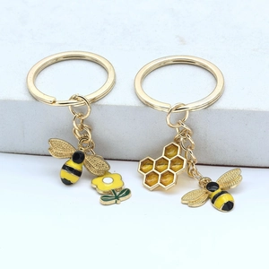 Détail de porte-clés abeille et nid d'abeille avec finition émail jaune doré