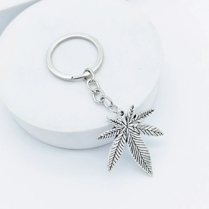 Vintage silver maple leaf keychain with serrated metal leaf pendant on white stand