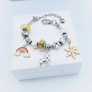 Detailed view of DIY charm bracelet with rainbow, unicorn, and snowflake charms on white box