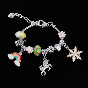 Detail of silver snake chain bracelet featuring rainbow unicorn and snowflake charms