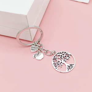 Détail d'un porte-clés arbre de vie argenté avec pendentifs en forme de cœur et pomme