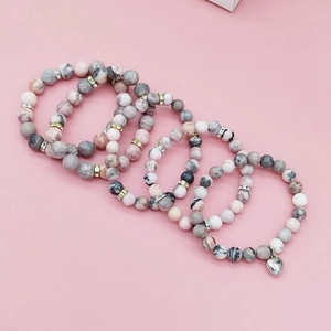 Five-piece pink zebra stone beaded bracelet set with heart charm on pink background