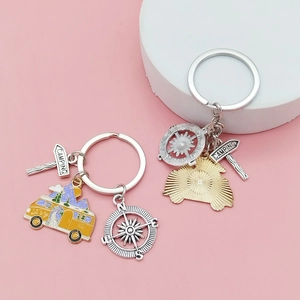 Porte-clés camping avec caravane RV, boussole et panneau routier sur fond rose doux