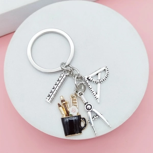 DIY stationery keychain with compass and ruler charms on a pink background