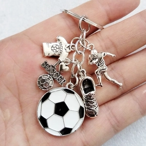 Fußball-Schlüsselanhänger mit Ball, Trikot, Schuh und Herzanhänger in der Hand gehalten