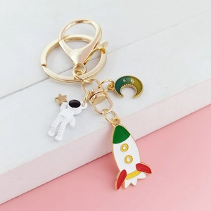 Porte-clés astronaute avec breloques fusée et lune sur fond rose et blanc élégant