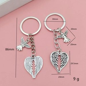 Porte-clés cœur et ailes d'ange en alliage argenté pour couple sur fond rose