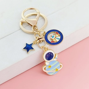 Détail d'un porte-clés astronaute doré avec pendentifs planète et finition émaillée