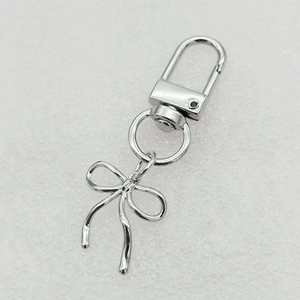 Silver metal bow keychain with lobster clasp and ring on textured background
