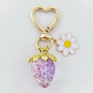 Détail du porte-clés fraise en résine violette avec fermoir cœur, marguerites et strass brillants