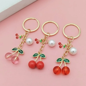 Detailed close-up of cherry keychains with pearls and red translucent fruit charms