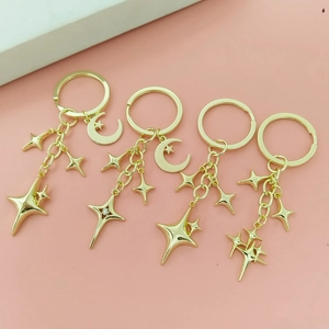 Close-up of four gold star and moon charms with rhinestones on a metal keychain set