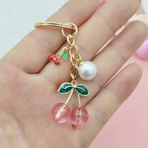 Detail of pink resin cherry keychain with gold metal ring and white pearl charm