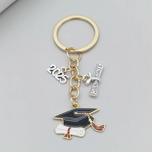 Gros plan du porte-clés de remise de diplôme 2025 avec breloques chapeau et parchemin