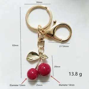 Golden cherry keychain with red resin charms and dimensions 82mm length on white background
