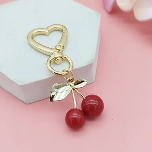 Close-up of golden heart clasp and red cherry charms on a white display stand