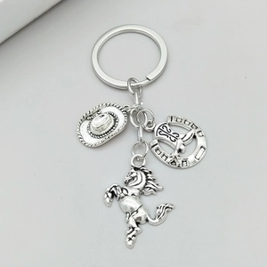 Detailed macro view of vintage silver cowboy hat, horseshoe, and horse charms on keychain