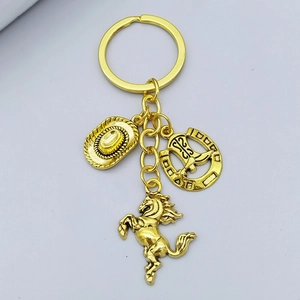 Close-up of golden western cowboy keychain with horse, hat, and horseshoe charms