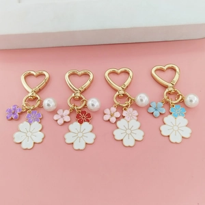 Detalle de llaveros de corazón con flores de cerezo, perlas y dijes de flores esmaltadas