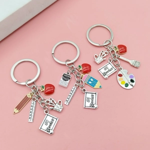 Teacher appreciation keychain set with red apple and pencil charms on pink background