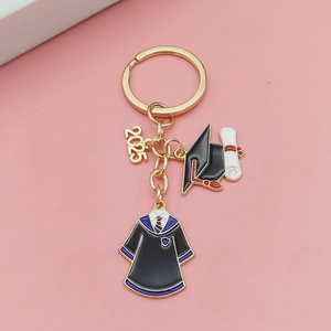 Détail du porte-clés de remise de diplôme 2025 avec pendentifs toque et robe dorés