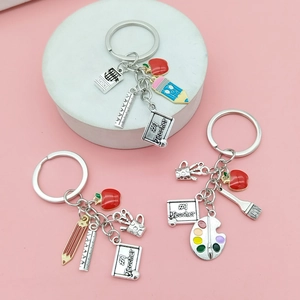 Teacher appreciation keychains with red apple, palette and pencil charms on pink background