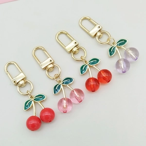 Detailed view of colorful acrylic cherry keychains in red, pink, dark red and purple