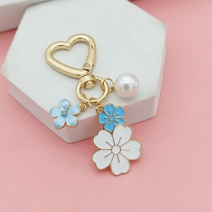 Primer plano de cierre de corazón dorado con flores de esmalte azul y perla elegante