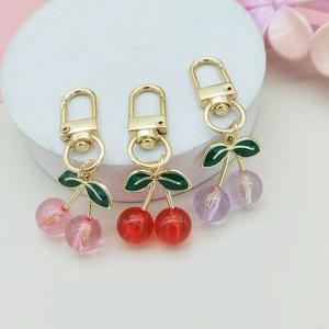 Close-up of pink, red, and purple acrylic cherry keychains with green enamel leaf detail