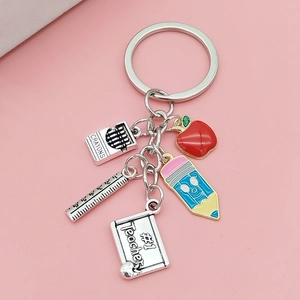 Macro detail of metal keychain featuring red apple pencil and #1 Teacher blackboard charms