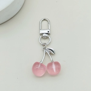 Detailed macro view of pink acrylic cherry keychain with silver metal clasp and leaf