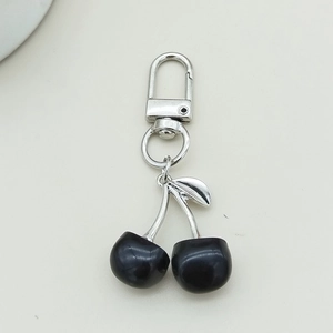 Detail shot of cherry-shaped keychain with shiny black globes and silver metal clip