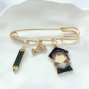 Macro detail of 2026 graduation brooch featuring alloy pencil and doctoral cap charms