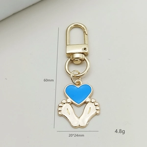 Detailweergave van de gouden sleutelhanger met babyvoetjes en blauwe hartbedel