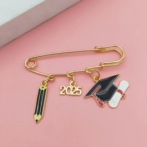 Detail of 2025 graduation brooch featuring alloy pencil and doctoral cap charms