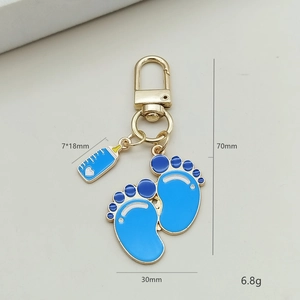 Baby thema sleutelhanger met blauwe emaille voetafdrukken en fles op goud metaal