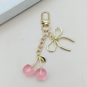 Détail du porte-clés cerise rose avec fermoir doré et élégant nœud papillon en métal