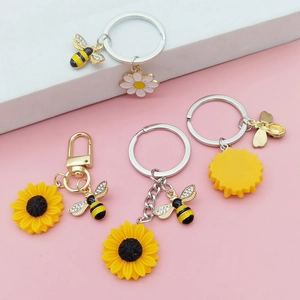 Vue détaillée des pendentifs tournesol et abeille sur des porte-clés dorés élégants