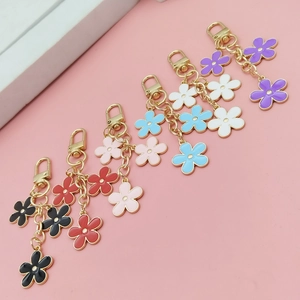 Close-up of six colorful enamel flower keychains with gold lobster clasps and chains