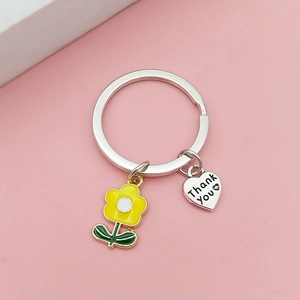 Close-up of metal keychain with yellow flower charm and Thank You engraved heart pendant