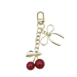 Porte-clés cerise 3D avec nœud en métal et perles rouges sur fermoir doré