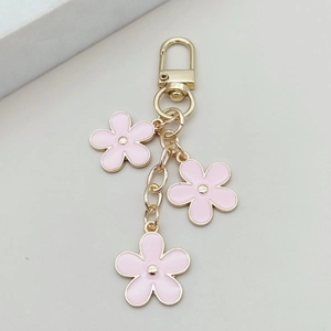 Detailed macro view of three pink enamel flowers on gold alloy keychain with lobster clasp
