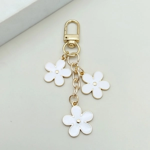 Detail of golden alloy keychain with three white enamel flower charms and D-ring buckle