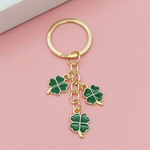 Détail du porte-clés trèfle vert porte-bonheur avec métal doré sur fond rose poudré
