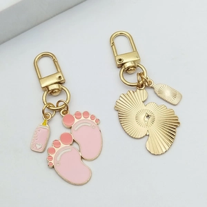 Close-up of golden baby bottle and pink footprint alloy charms for keychain DIY
