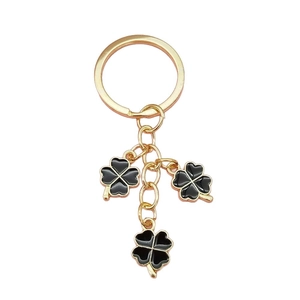 Porte-clés doré avec trois pendentifs trèfle à quatre feuilles noirs et grand anneau en métal