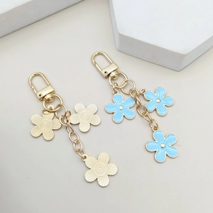 Detailed view of light blue enamel flower charms with gold lobster clasp on white stone