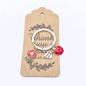 Vue détaillée des breloques pomme et fleur sur un porte-clés avec pendentif cœur