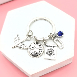 Detailed close-up of travel keychain with silver airplane, passport charm and blue gem