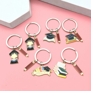 6-piece graduation keychain set with academic caps and books on a pink background